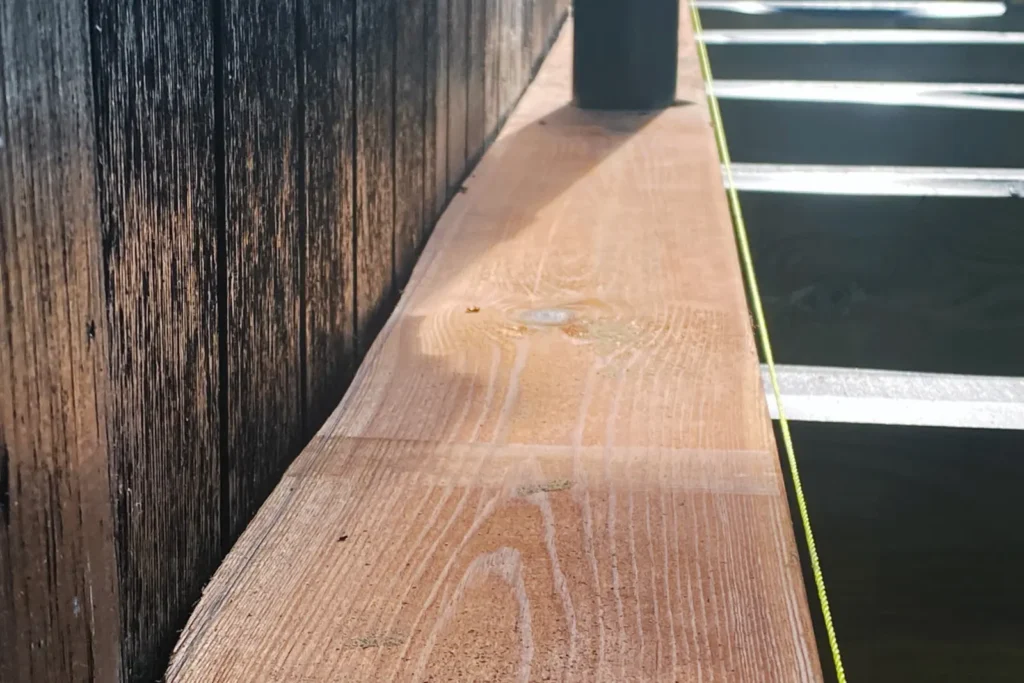 Det 17,5 meter lange terrassedæk i brunimprægneret fyr, som løber skarpt og parallelt langs sommerhusets facade i Rågeleje.