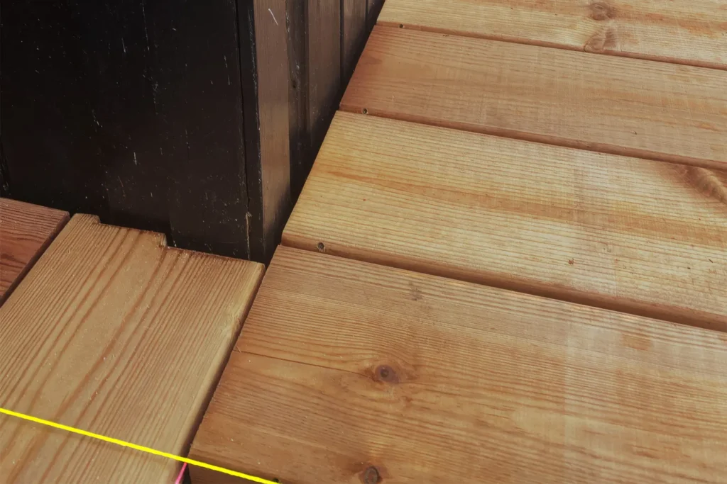Detalje af hvordan terrassebrædderne er tilpasset helt tæt omkring sommerhusets eksisterende udvendige hjørner og vinkler i Rågeleje.