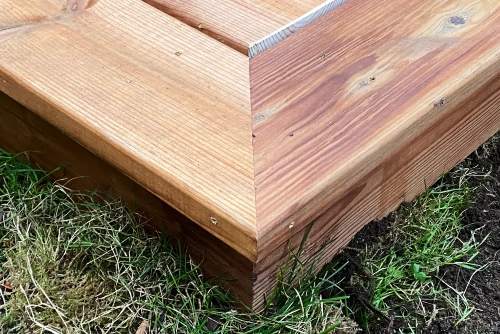 Nærbillede af en hjørnesamling skåret i smig på terrassens ramme af brunimprægneret fyr ved sommerhus i Rågeleje.